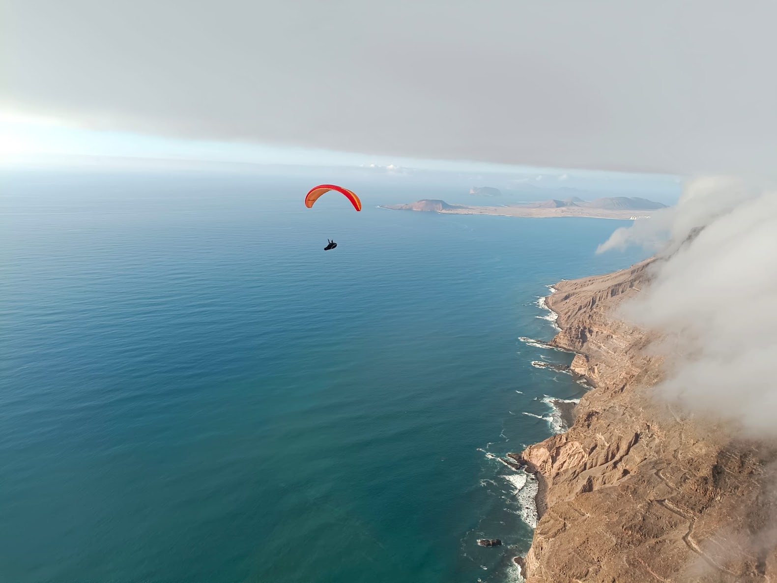 Paraglider soaring over Lanzarote's dramatic coastline